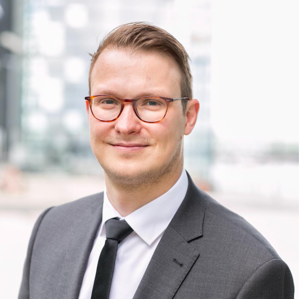 Dr. Daniel Trauth wearing glasses and a suit